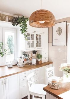 a kitchen with white cabinets and wooden counter tops, plants on the window sill