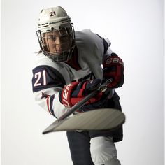 a hockey player is holding his stick and ready to hit the ball in mid air