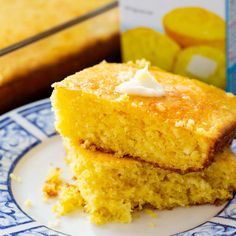 two pieces of cornbread on a blue and white plate with a carton of milk in the background