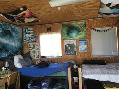 a dorm room with two beds and pictures on the wall above them, along with other clutter