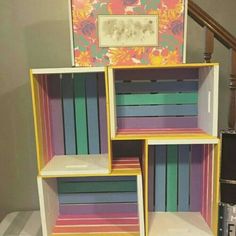 three colorful bookshelves stacked on top of each other in front of a stair case