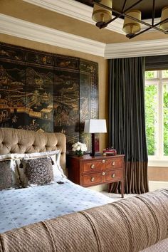 a bedroom with a bed, dresser and large painting on the wall above it's headboard