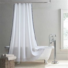 a white bath tub sitting under a window next to a shower curtain with black trim