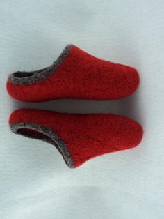 pair of red slippers sitting on top of white sheeted paper with grey trim