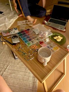 a person sitting at a table with many items on it and a laptop in the background