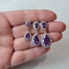 "These beautiful handmade classic amethyst purple cubic zirconia CZ teardrop dangle bridal earrings are available in three sizes and feature CZ halo pear drops dangling from CZ halo pear posts. The pear stones in the drops and posts are circled by a halo of small round brilliant cut CZs. All settings and findings are white gold and rhodium plated. These earrings are perfect for a romantic or vintage inspired look. Really beautiful quality and amazing sparkle perfect for your wedding or special occasion! For pierced ears.  Measurements: Small:  1\" L x 3/8\" W, bottom pear stone measures 6x8mm Medium:  1-1/4\" L x 1/2\" W, bottom pear stone measures 9x12mm Large:  1-3/8\" L x 3/8\" W, bottom pear stone measures 10x15mm Choose your size from the pull-down menu. I also have posts with clear s Purple Dangle Bridal Earrings For Formal Occasions, Purple Sparkling Stone Drop Earrings, Purple Sparkling Drop Earrings, Purple Dangle Bridal Earrings, Classic Lavender Jewelry For Wedding, Dazzling Amethyst Jewelry For Wedding, Purple Drop Jewelry For Anniversary, Purple Pear-shaped Jewelry For Wedding, Purple Cubic Zirconia Earrings For Wedding