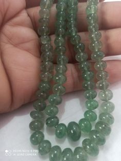 the green beads are being held by someone's hand