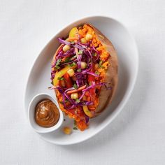 a white plate topped with a taco covered in veggies and sauces