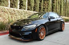 a black car with orange rims parked on the street