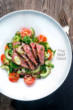 a white plate topped with meat and veggies on top of a wooden table