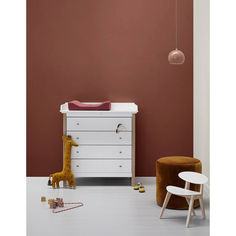 a baby's room with a white dresser, brown chair and giraffe toy