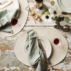 two plates with napkins and silverware on top of a wooden table next to flowers