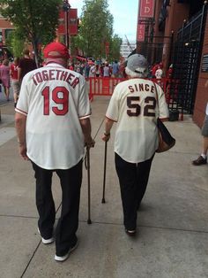 two baseball players walking down the street with their canes in hand and people standing behind them