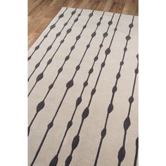 a white and black rug with lines on the floor in front of a wooden floor