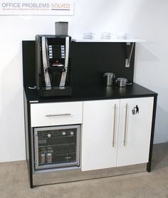 a coffee machine sitting on top of a white cabinet next to a wall mounted oven