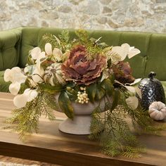 a vase filled with flowers sitting on top of a wooden table next to a green couch