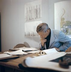 a man sitting at a table with papers and pens in front of him looking down