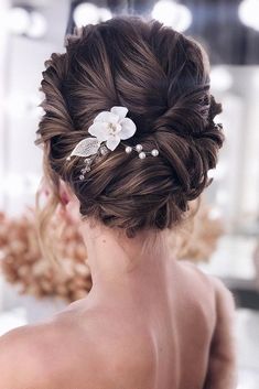 the back of a woman's head with flowers and pearls in her hair,