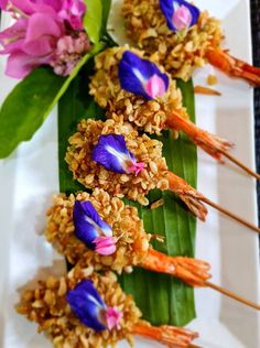 some food is laying out on a white plate with purple flowers and green leaves next to it