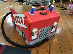 a firetruck made out of cardboard sitting on top of a hard wood floor