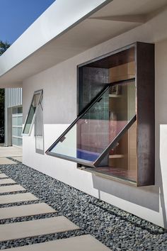 an open window on the side of a building next to gravel and rocks in front of it