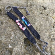 two beaded bracelets are laying on the ground next to some rocks and stones