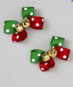 two red, green and white bows with gold bells on each bow are sitting next to each other