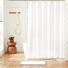 a white shower curtain with green scalloped trim and a potted plant next to it