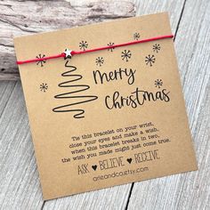 a christmas card with a red string attached to it on top of a piece of wood