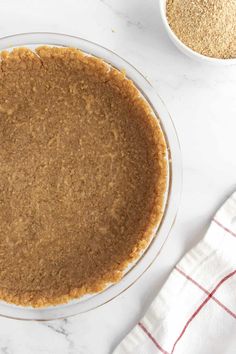 a pie sitting on top of a white counter next to a bowl of oatmeal