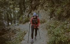 a woman hiking up a trail in the woods with her backpack and skis on