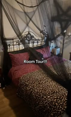 a bed with a leopard print comforter and black netting over it's head