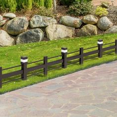 a black and white fence in front of some rocks on the side of a road