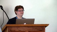 a man standing at a podium with a laptop on his lap