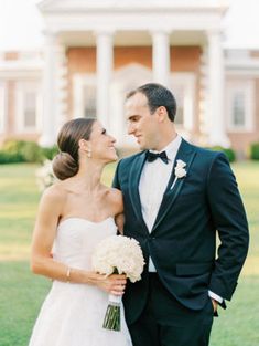 a bride and groom standing in front of a large building with columns on the side