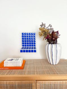 a vase with flowers on top of a wooden table next to a book and magazine