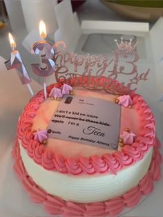 a birthday cake with pink frosting and two lit candles on the top it says, happy 3rd birthday