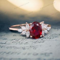 a close up view of a ring with a red stone and white diamonds on it