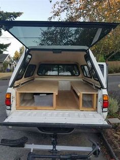 the back end of a white van with an open trunk and storage compartment in it