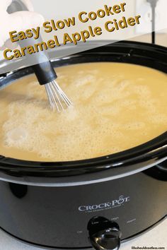 an easy slow cooker caramel apple cider is being stirred with a whisk