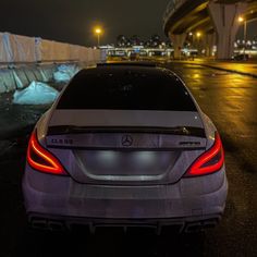 the back end of a car parked in front of an overpass at night time