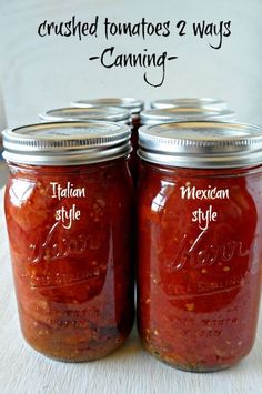 two mason jars filled with red sauce sitting on top of a table