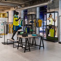 a man in yellow shirt and blue shorts standing next to a table with clothing on it