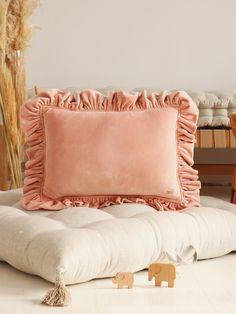 an elephant figurine sitting on top of a white couch next to a pink pillow