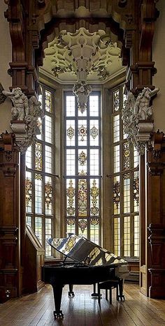 a grand piano sitting in the middle of a room with stained glass windows and wood flooring