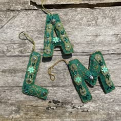 three pieces of green metal with flowers and beads hanging from strings on wooden planks