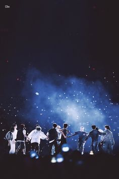 a group of people standing on top of a stage under a sky filled with stars