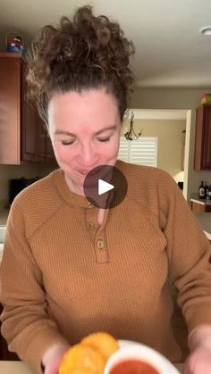 a woman is holding a plate with oranges on it and making a funny face