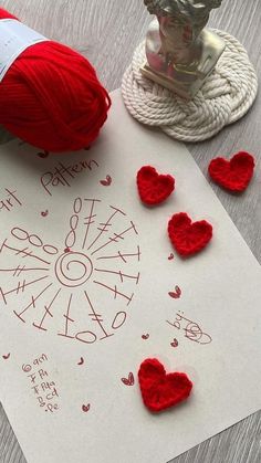 yarn and crochet hearts are on the table next to a piece of paper that says it is valentine's day