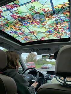 a woman driving a car with a colorful ceiling in the back seat and another vehicle behind her